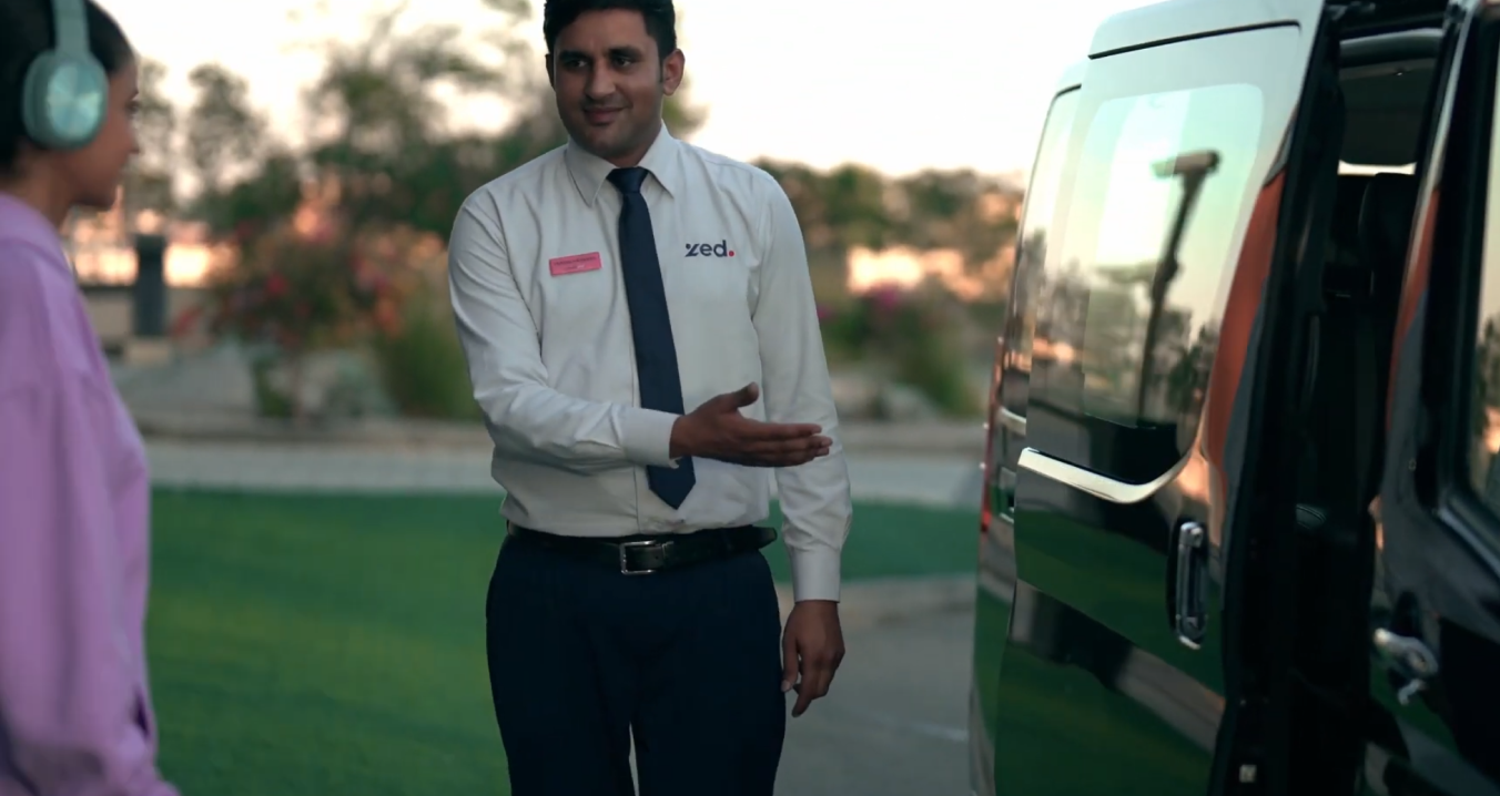 A Zed driver welcoming a customer into his car.
